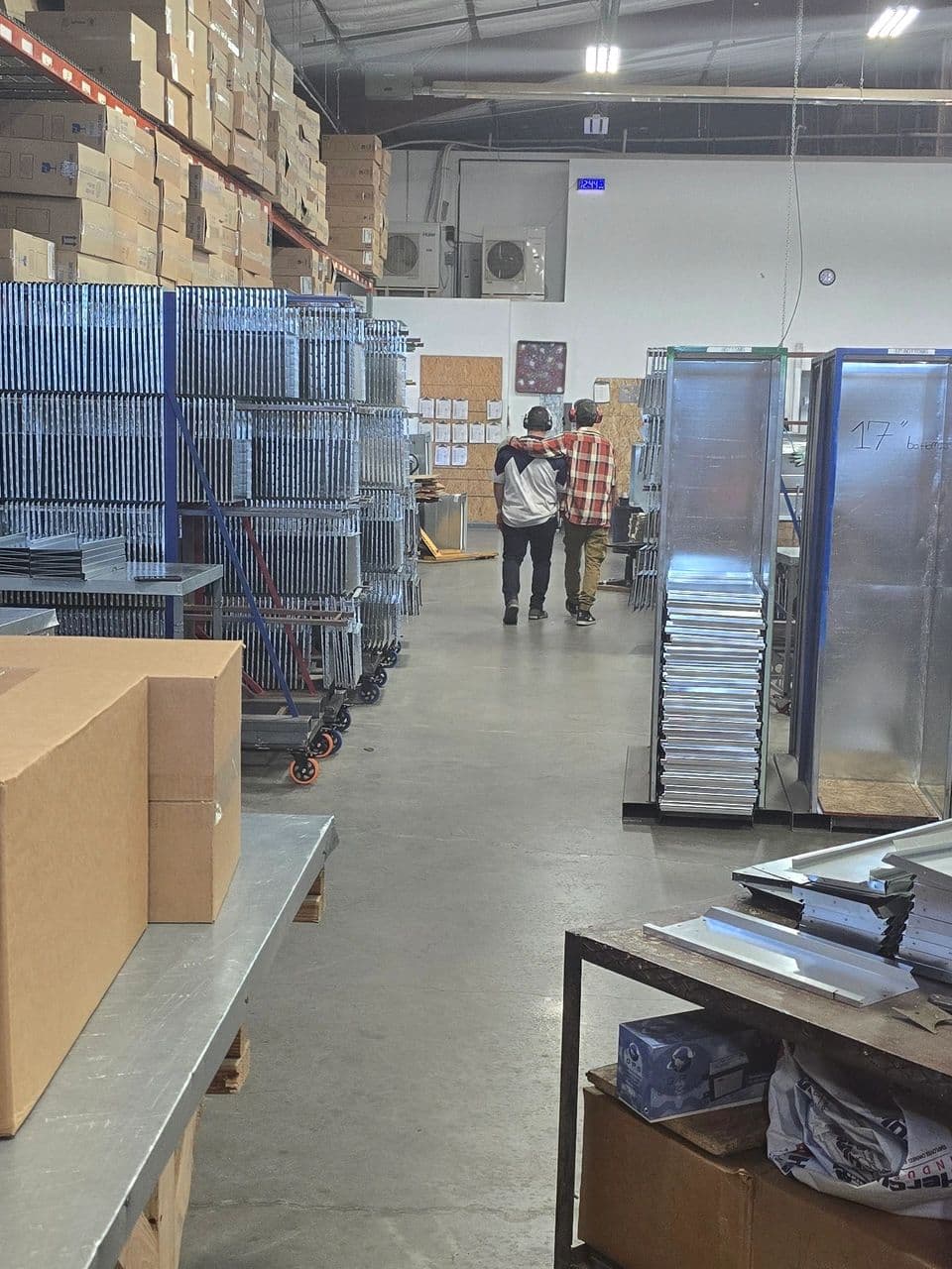 High-volume production floor with racked sheet-metal parts and crew